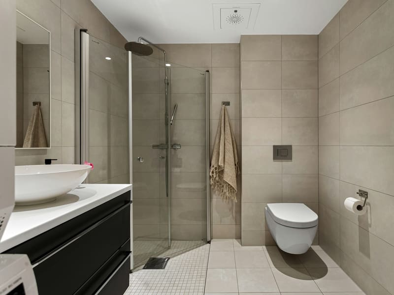 Modernes Bad mit Glasdusche, Wand-WC und Waschtisch in warmen Grautönen